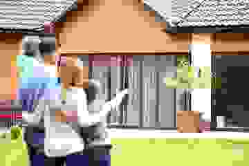Family standing outside a house pointing and looking at it happily