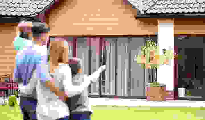 Family standing outside a house pointing and looking at it happily