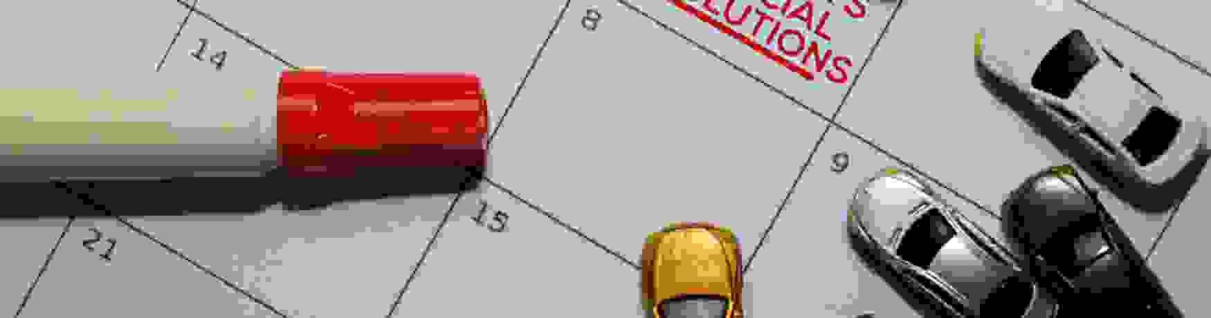 New Years Financial Resolutions on calendar with a marker and model cars