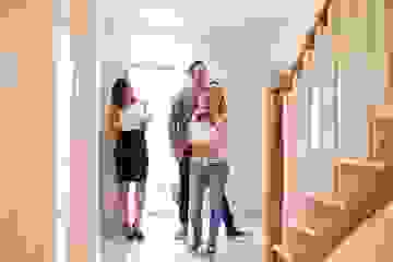 Young family with a baby walking into a house with a real estate agent