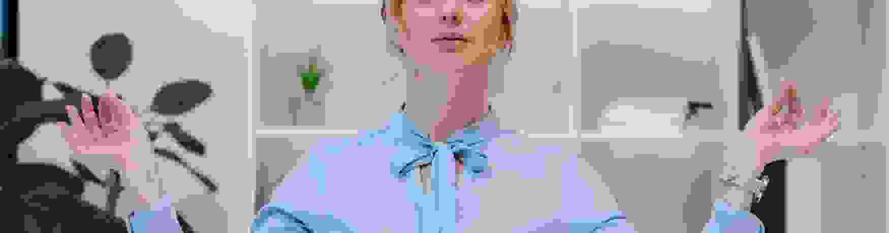 Woman standing balancing a book on her head with hands out and eyes closed