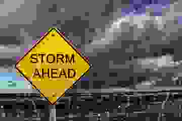 Warning sign of a storm ahead with raindrops in foreground and thunderheads in the background