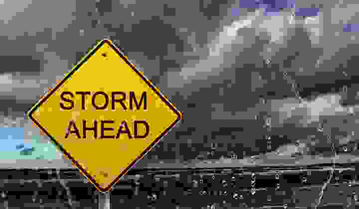 Warning sign of a storm ahead with raindrops in foreground and thunderheads in the background