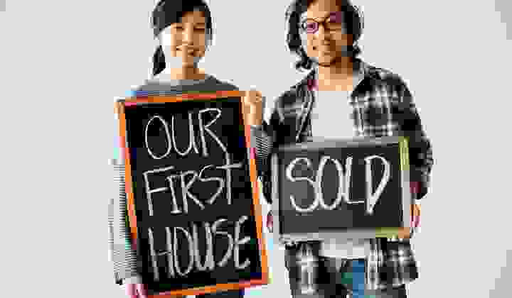 Young couple sand with blackboards announcing that they have sold their first house