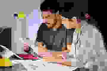 Concerned man and woman looking over their financial information with a calculator at home