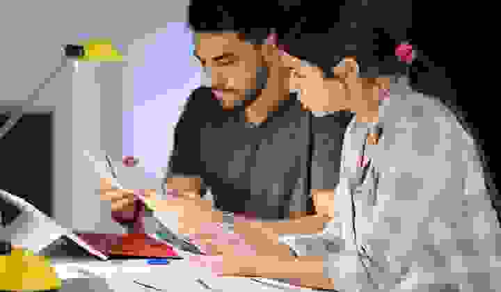 Concerned man and woman looking over their financial information with a calculator at home