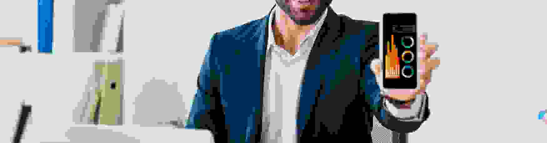 Young businessman in suit, with an open laptop and phone, showing us graphs