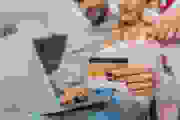 A soft focus image of a couple looking at a laptop holding a credit card in the foreground