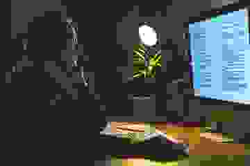 Woman working on her computer at night and talking on her cellphone at a home office