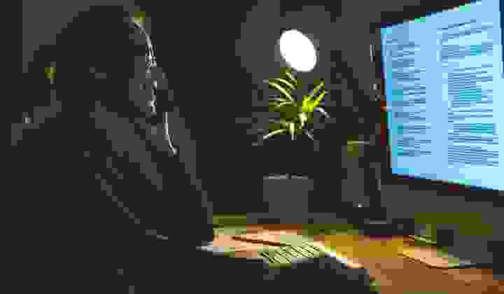 Woman working on her computer at night and talking on her cellphone at a home office