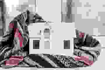 House model wrapped in a plaid scarf on a white windowsill