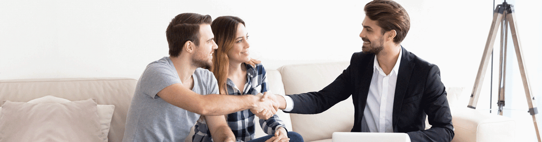 Couple shaking hands with a business man on a couch