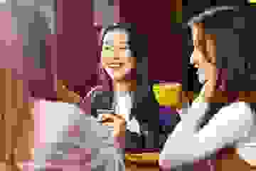 Three women at a cafe laughing and drinking coffee