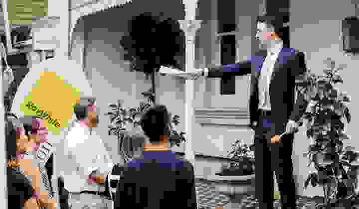 An auctioneer calls out a bid at an onsite real estate auction with a group of buyers gathered