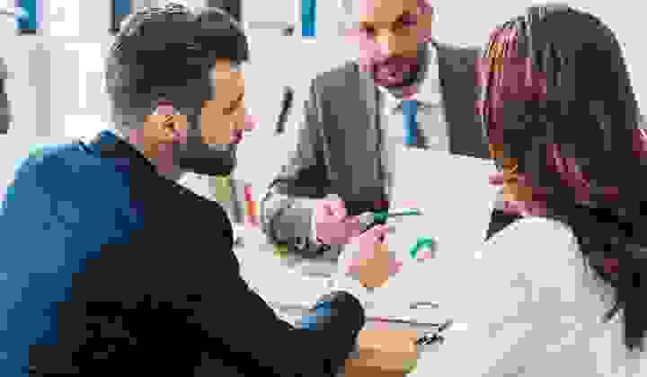 Young couple talking over financial charts with their mortgage adviser