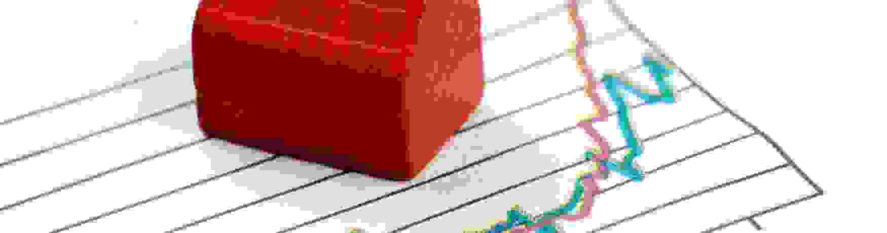 Little red Monopoly house on charts showing financial growth trends