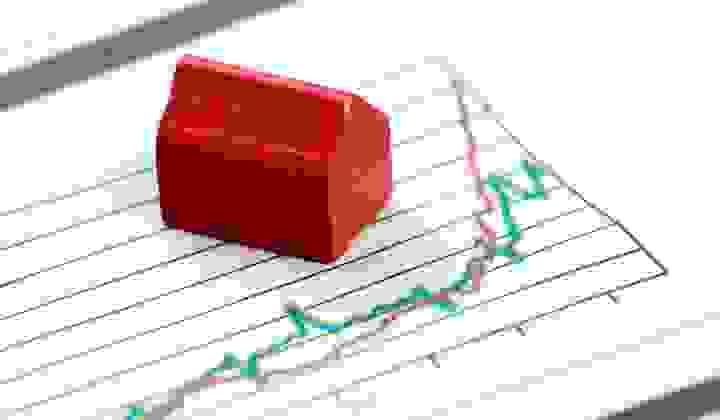 Little red Monopoly house on charts showing financial growth trends