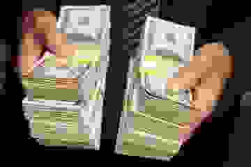 Close up photo of stacks of American notes being held by a man in a suit