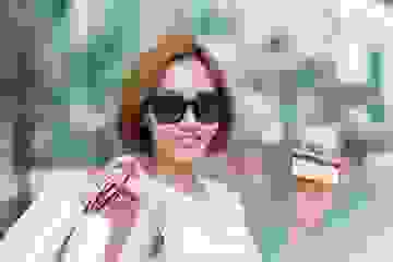 Smiling woman wearing sunglasses and holding lots of shopping bags and her credit card
