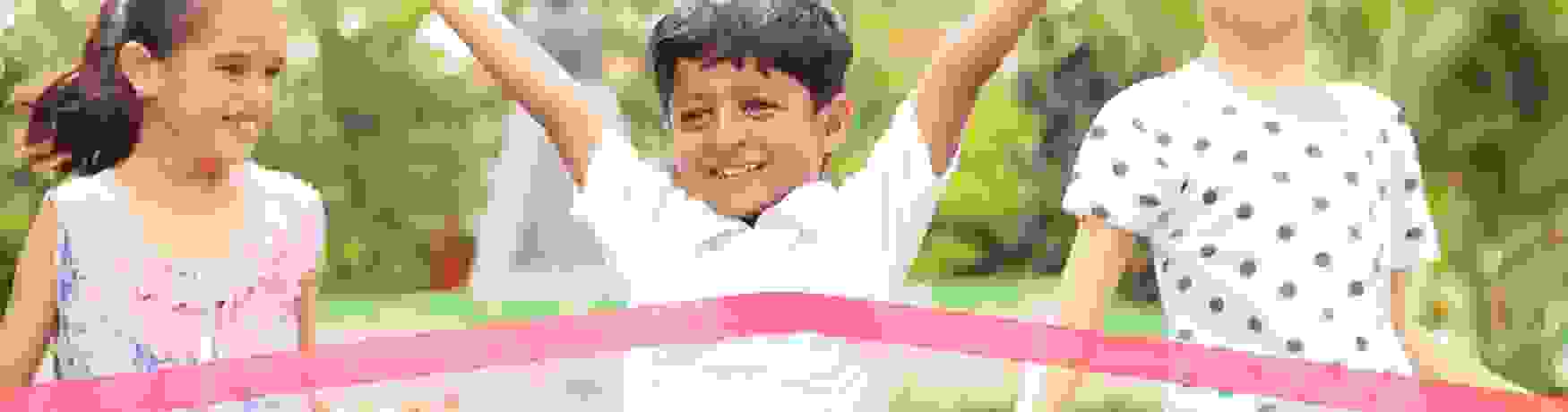 Young boy winning a race with two friends behind him