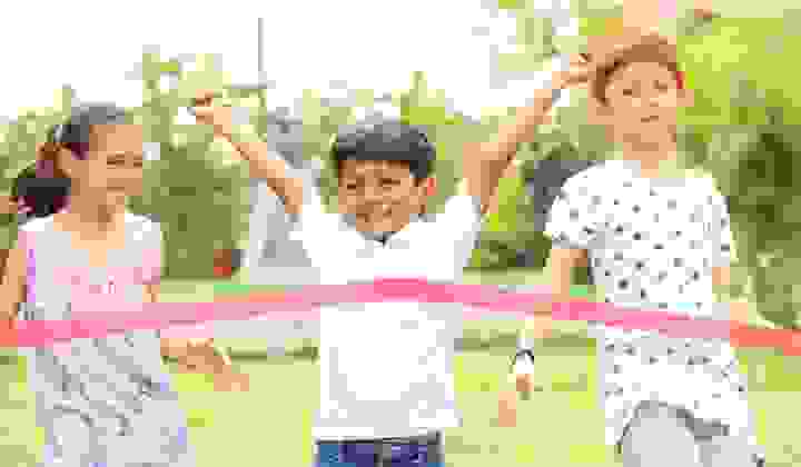 Young boy winning a race with two friends behind him