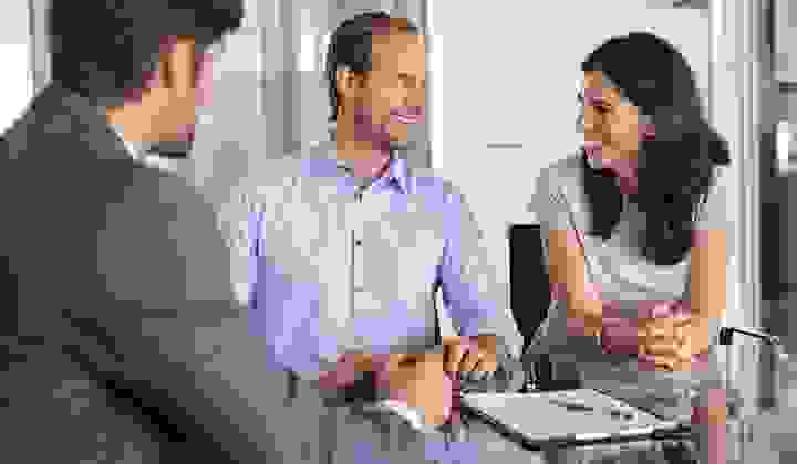A man and woman smile at each other after talking to their mortgage adviser in his modern office