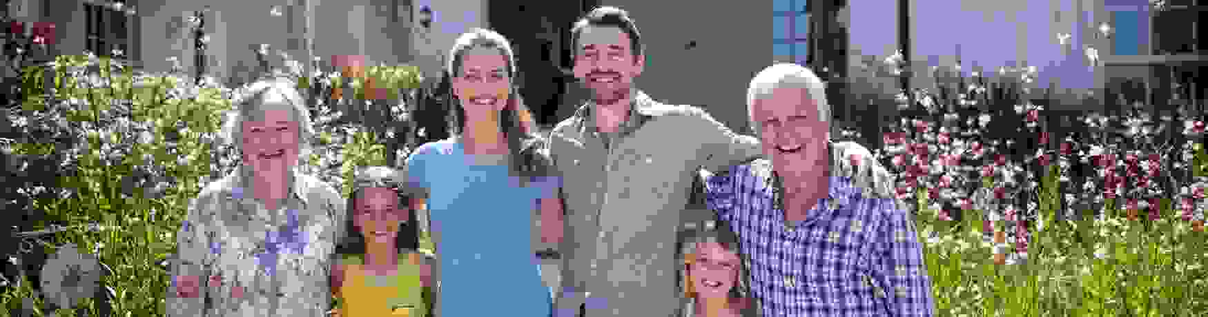 Smiling family standing with arms around each other outside a house