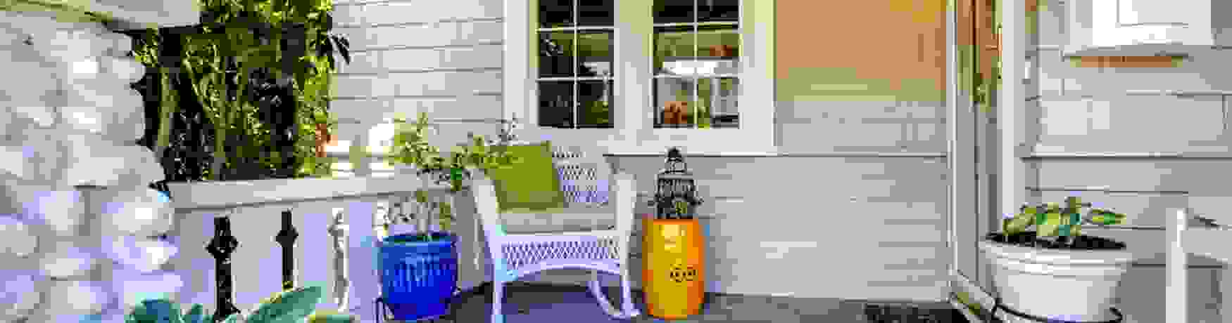 Welcoming front entrance to a house with plants and a wicker chair with cushions