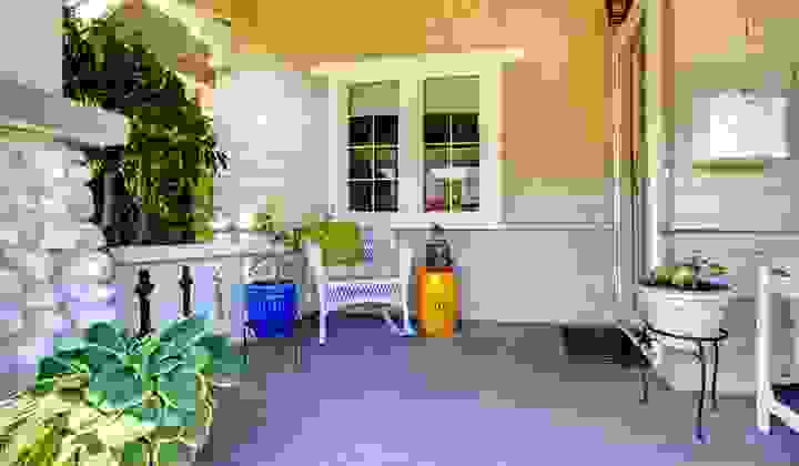 Welcoming front entrance to a house with plants and a wicker chair with cushions