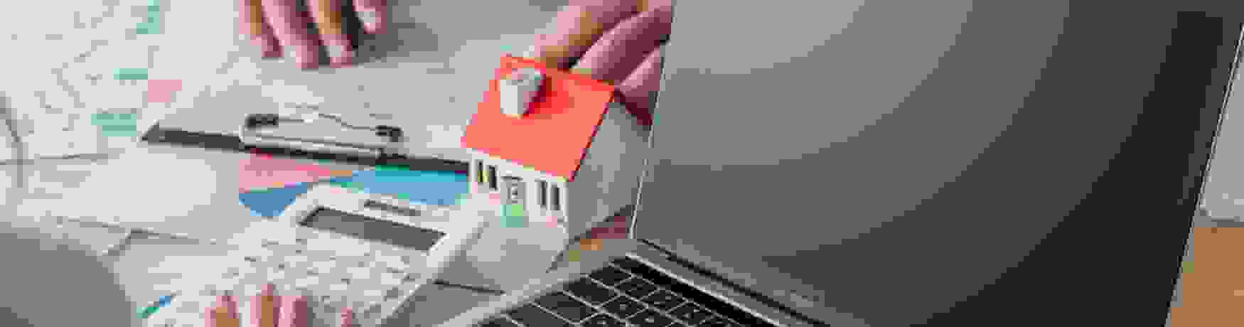 Two people looking over real estate paperwork with a calculator and open laptop