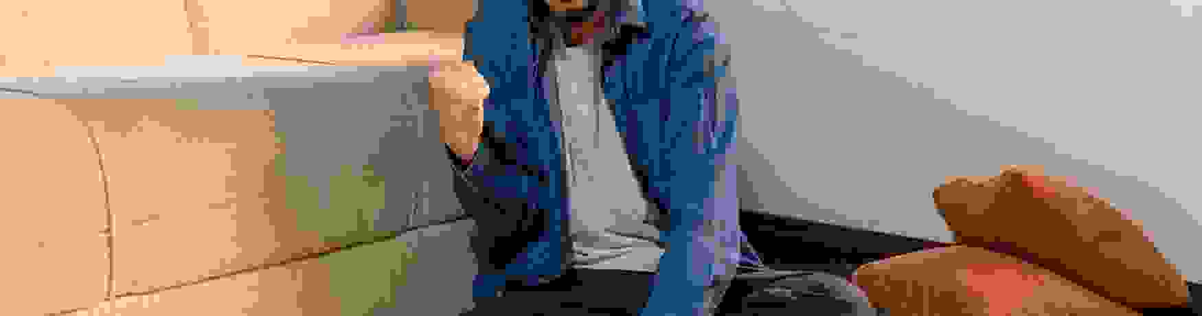 Man sitting cross legged in his lounge looking at his laptop and doing a fist pump