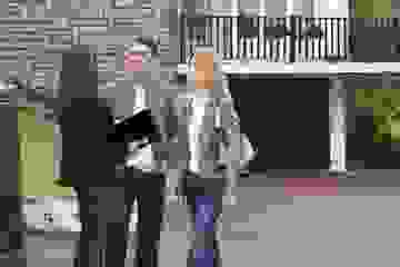 Couple discusses plans with a real estate agent outside a house