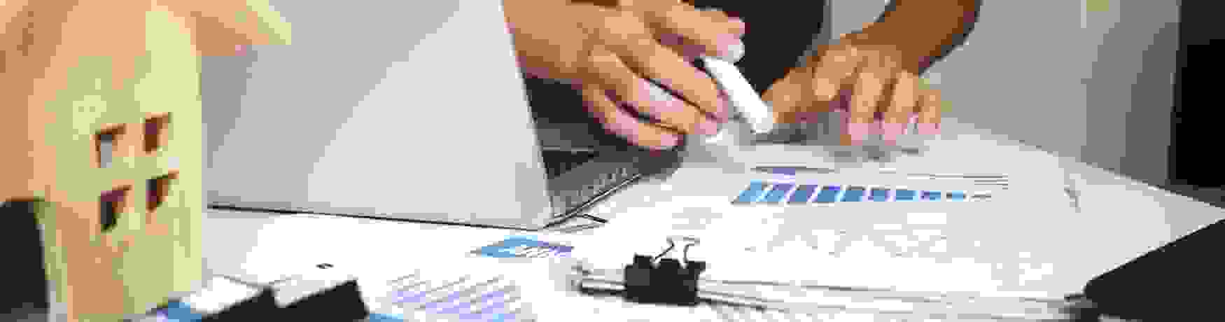 Soft focus shot of a man at his desk with laptop open and financial paperwork in front of him