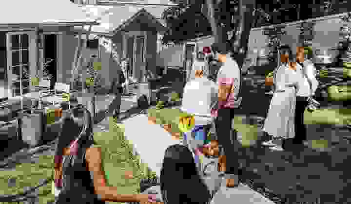 A group of potential buyers gather at an onsite auction while the auctioneer calls out bids and one woman raises her paddle.