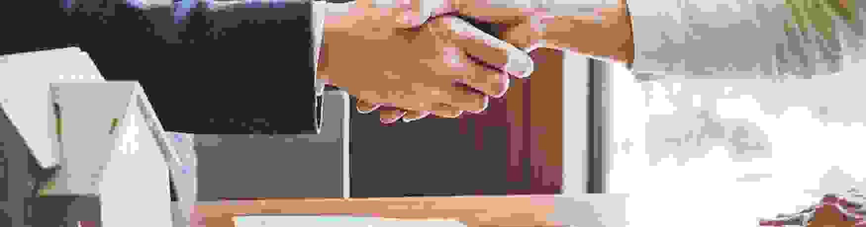 Mortgage adviser and client shake hands over a contract
