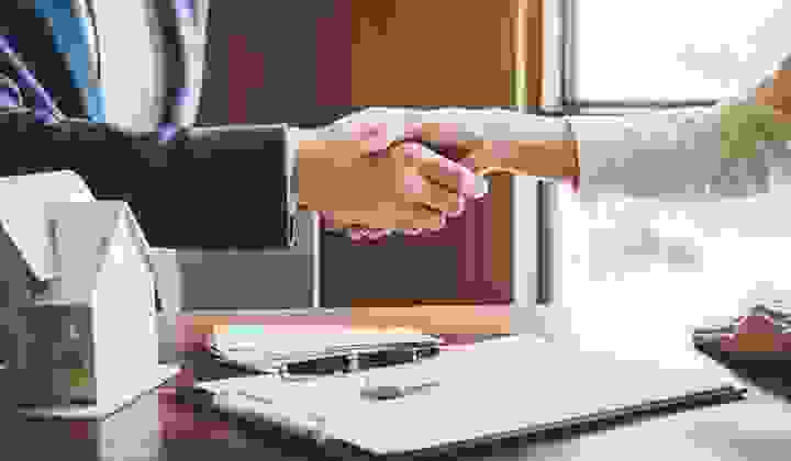 Mortgage adviser and client shake hands over a contract