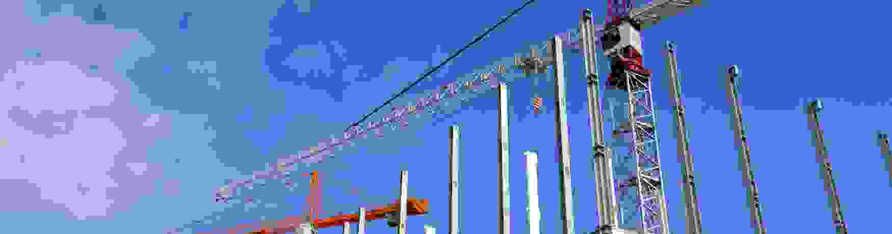 Cranes on a construction site against a bright blue sky