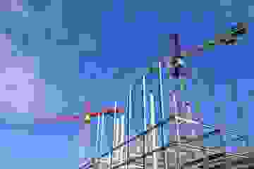 Cranes on a construction site against a bright blue sky