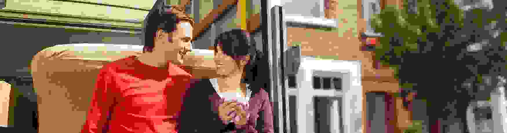 Young couple resting on the back of a removals van while moving into their new home
