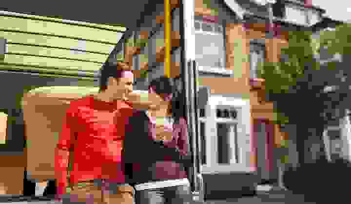 Young couple resting on the back of a removals van while moving into their new home