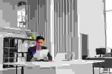 Asian businessman reading over documents in a large modern office