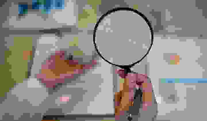 Woman looking at mortgage loan documents through a magnifying glass