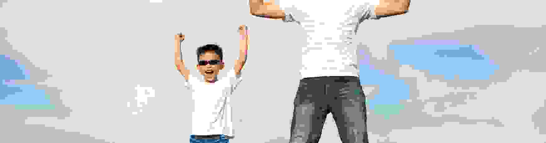 Father and son standing on horizon in powerful superman pose