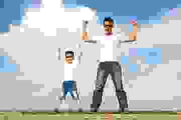 Father and son standing on horizon in powerful superman pose