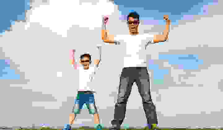 Father and son standing on horizon in powerful superman pose