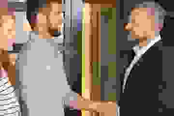 Young couple shaking hands with a property manager outside a house
