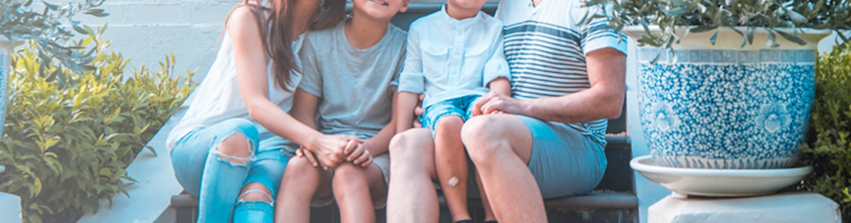 Mixed race family sitting on the steps outside their house