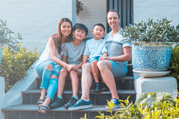 Mixed race family sitting on the steps outside their house