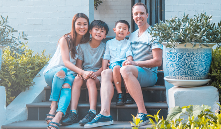 Mixed race family sitting on the steps outside their house