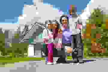 Smiling family group outside their new home on a sunny day